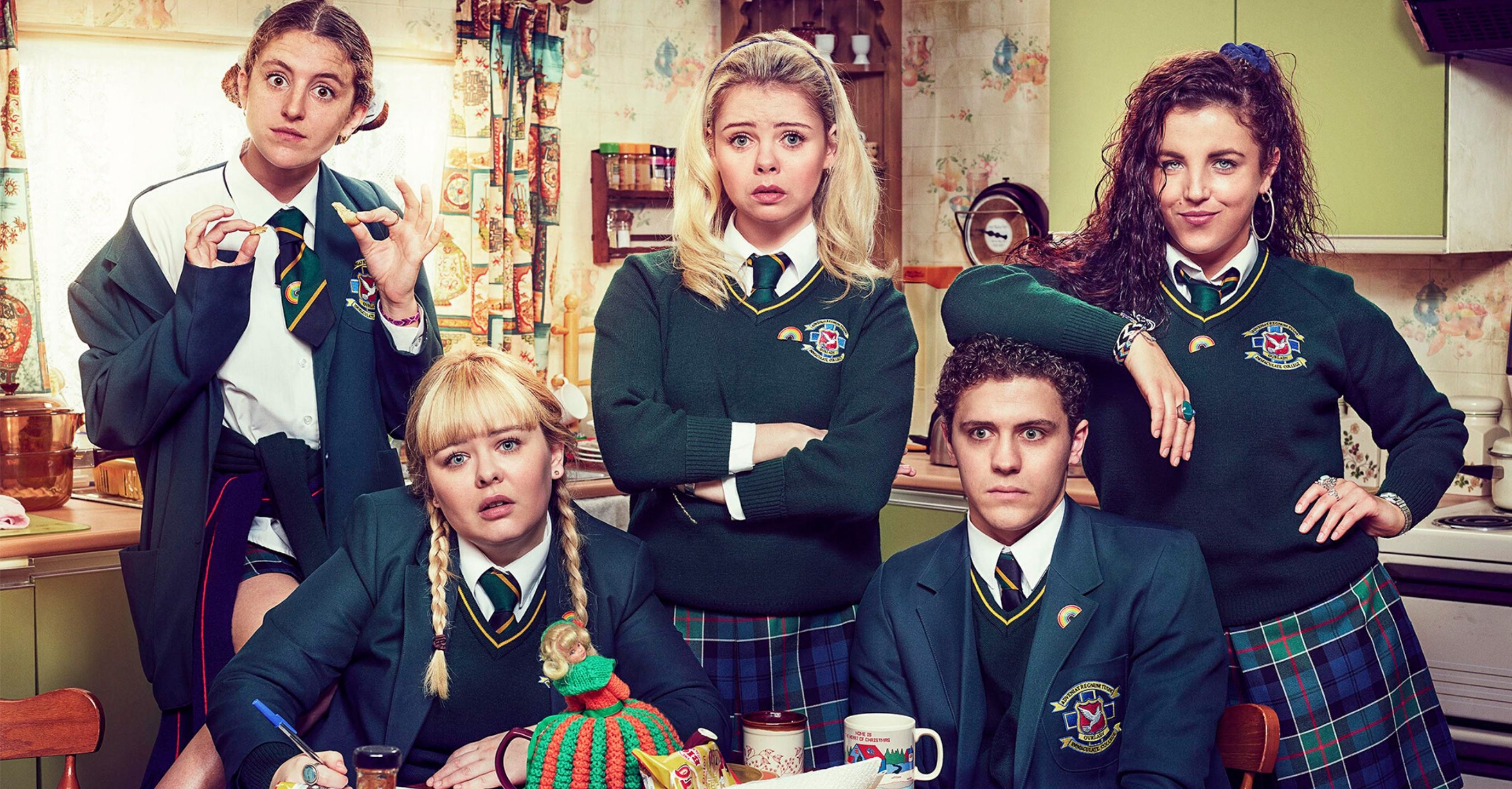 Cast of Derry Girls in school uniform stood in a kitchen