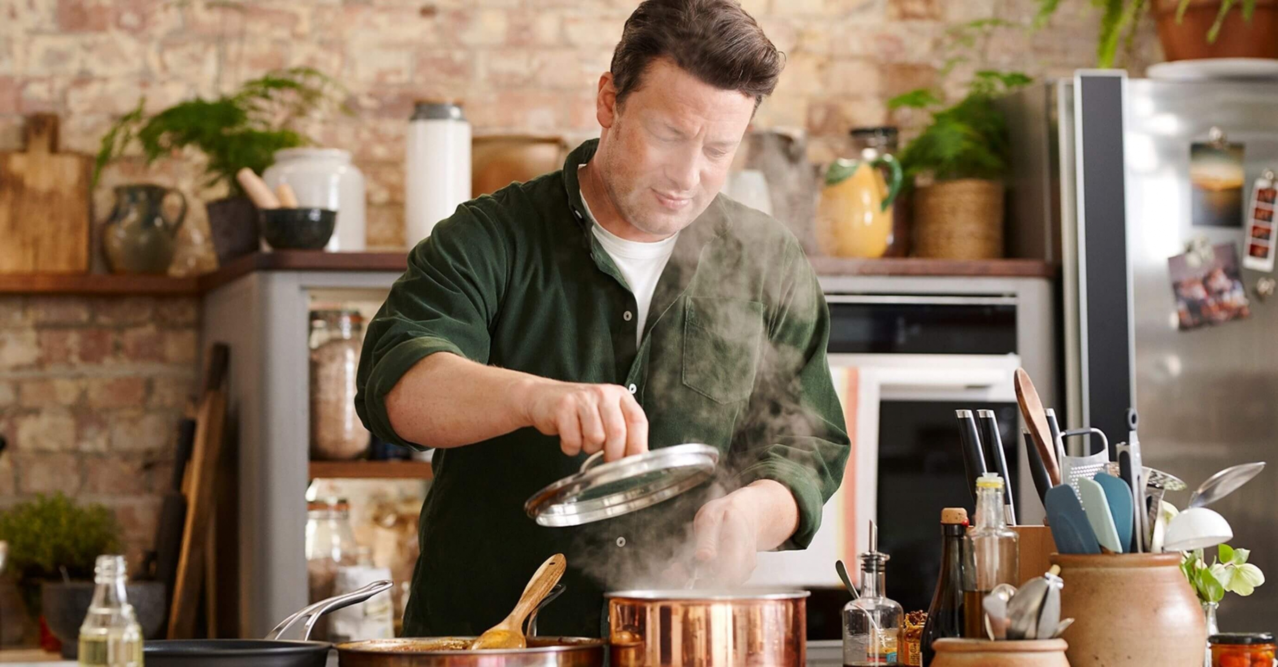 Jamie Oliver, presenter of “Keep cooking and carry on” lifts the lid of a steaming saucepan.