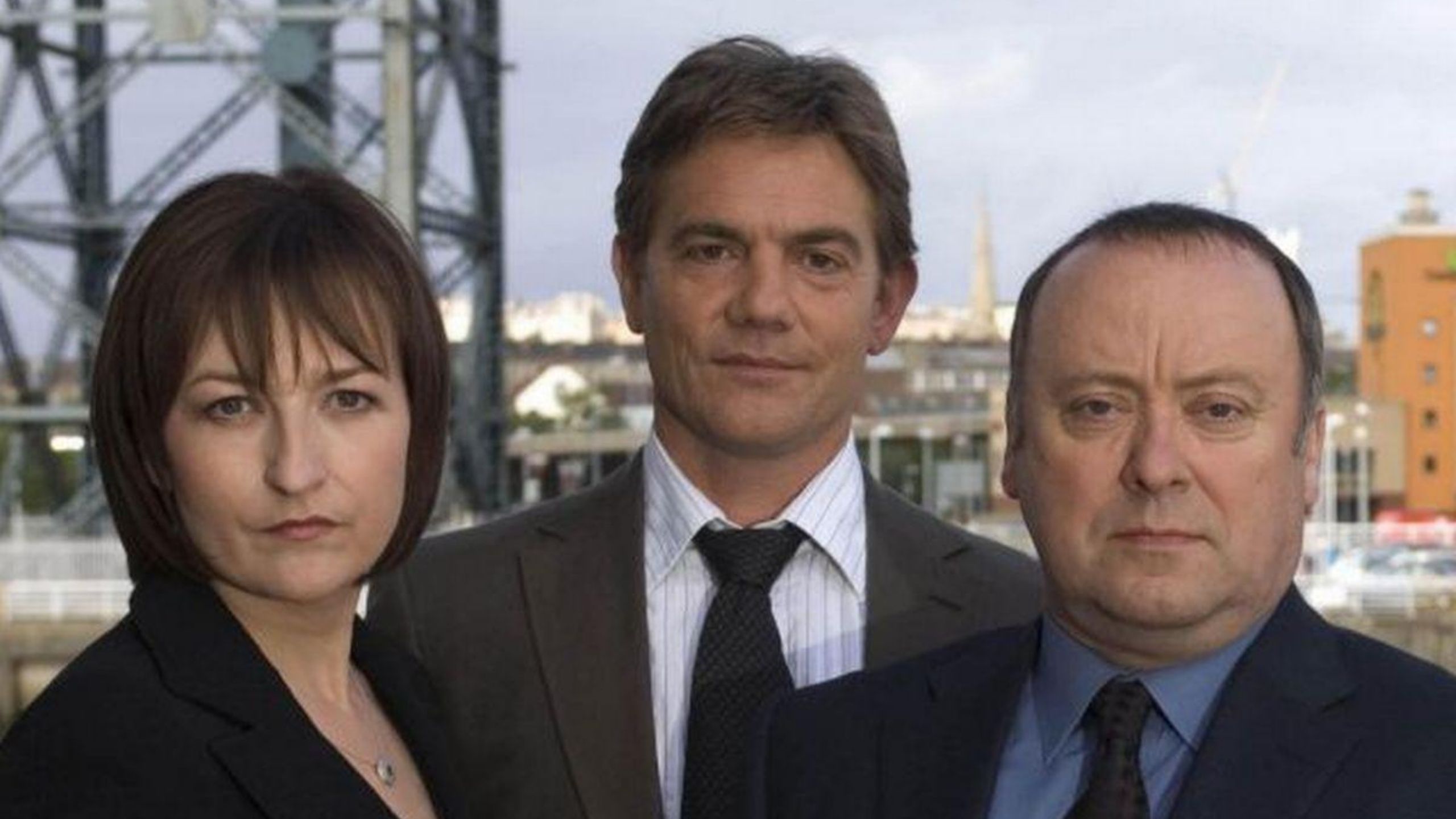 Cast of Taggart dressed in Suits with the Glasgow skyline 