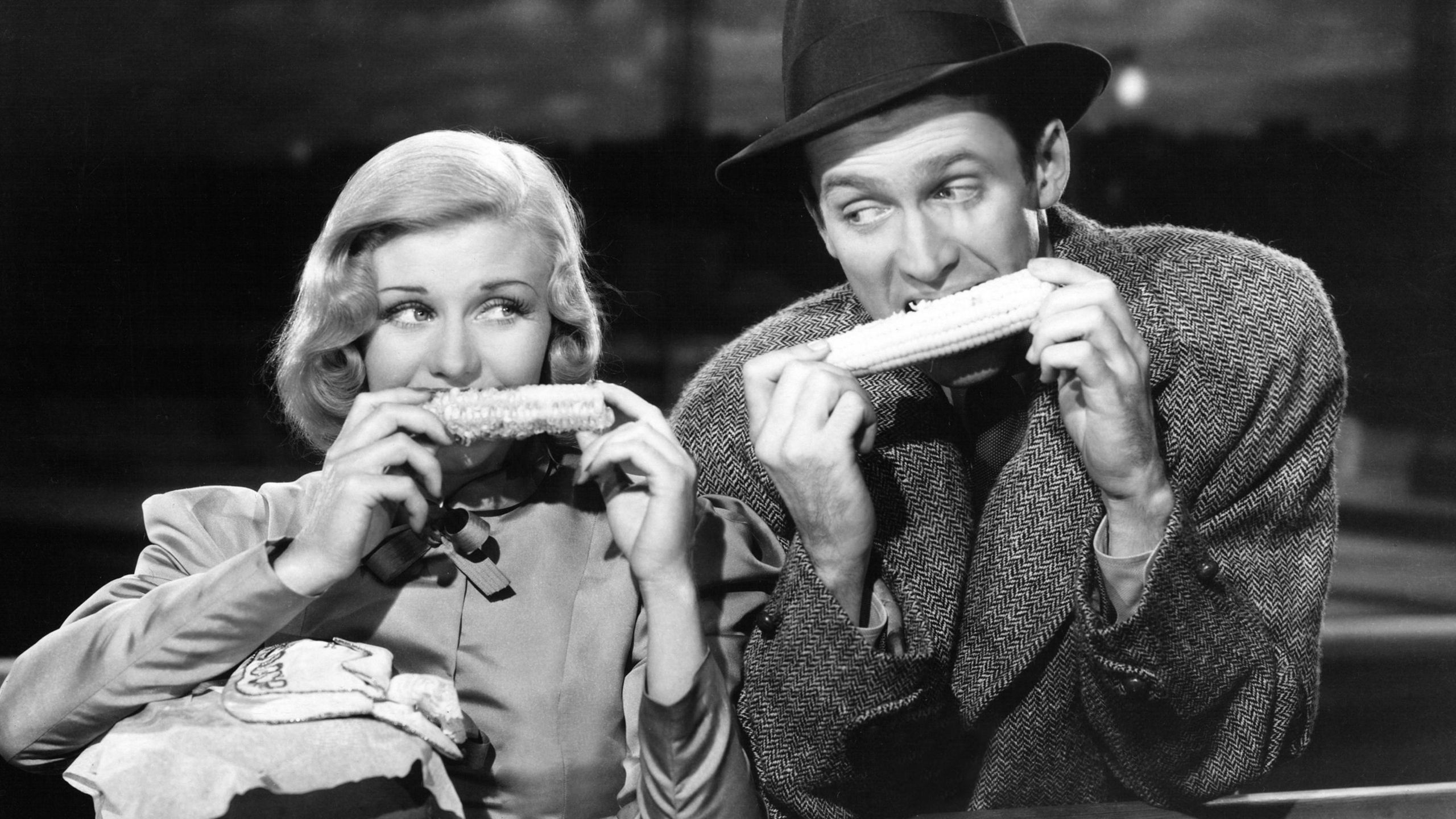Black and white image of a man and a woman eating corn on the cob 