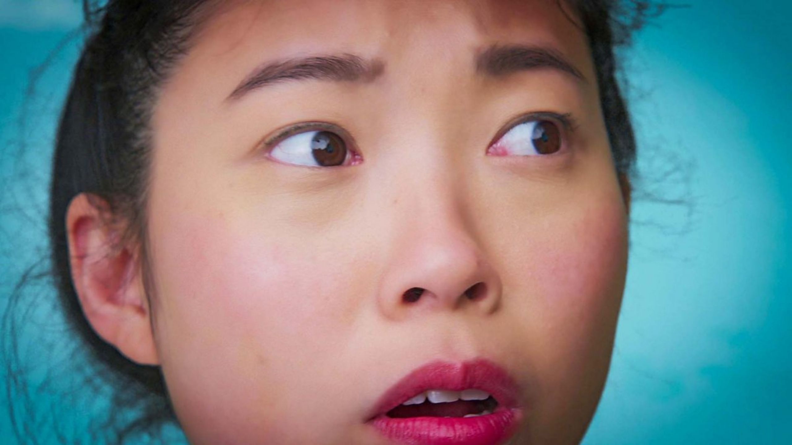 A close up image of Asian-American Awkwafina looking comically dazed with flyaway hair 