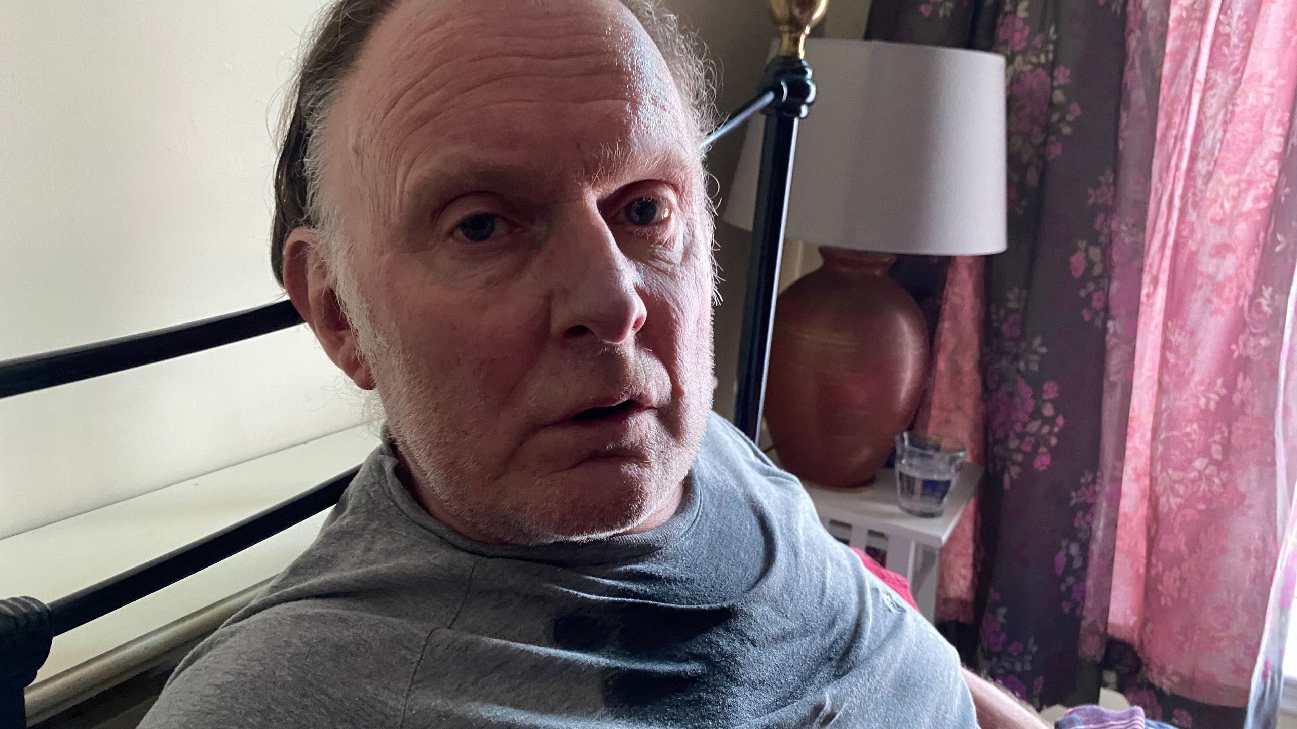 Robert Glenister sits on a bed in his pyjamas