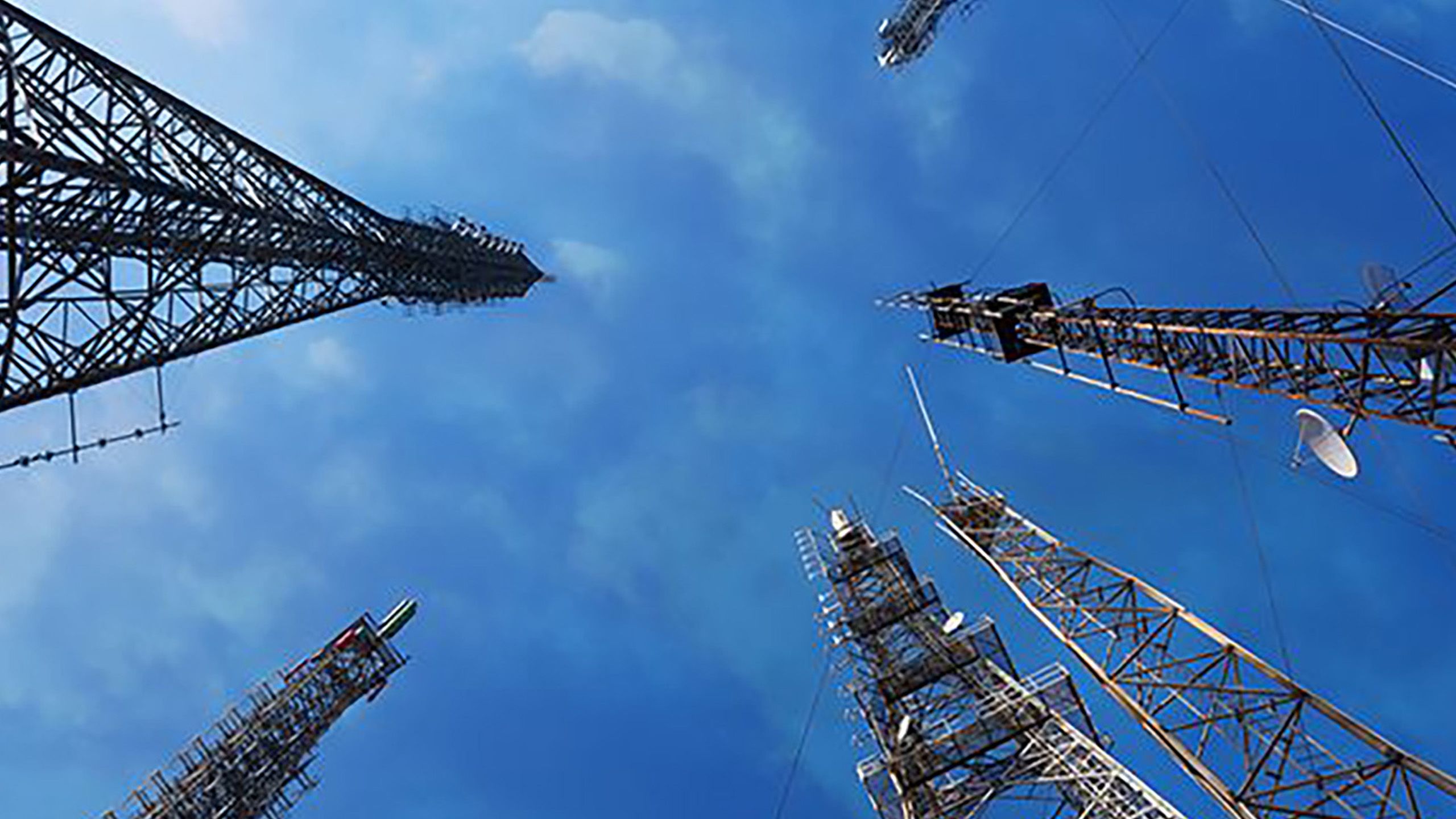 An aerial view looking up inside a group of TV transmitters against a blue sky.