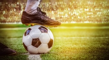 Close up of a football player with foot placed on top of a football