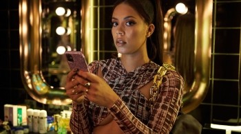 Young Black woman in a bathroom texting on her smartphone