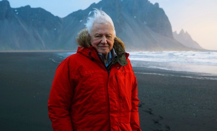 Sir David Attenborough stood on a mountainous coast