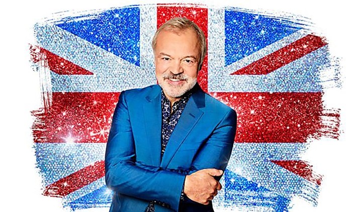 Headshot of Graham Norton, arms folded and standing in front of a Union Jack flag
