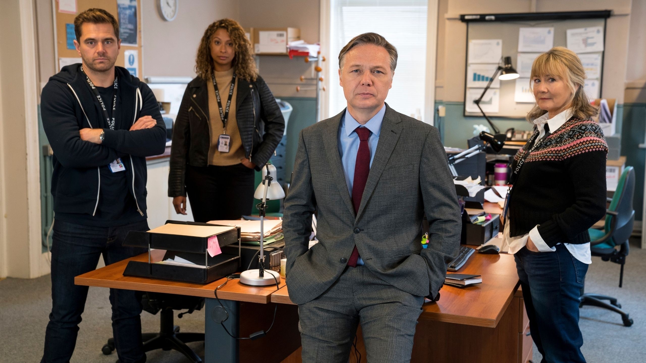 A team of police detectives standing by their desks