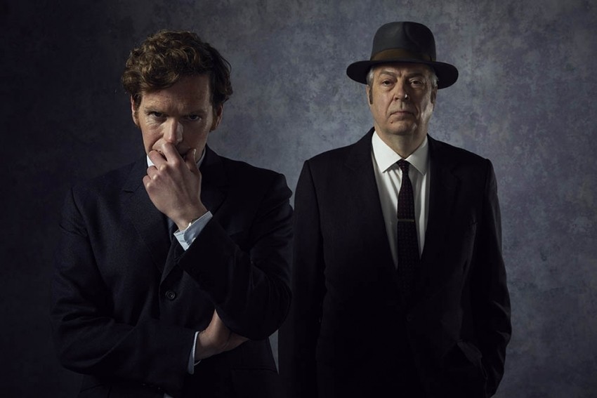 Two detectives in suits looking pensively at the camera