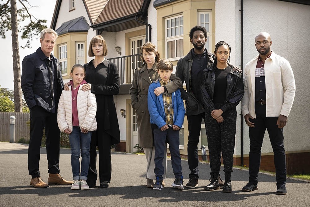 Cast of Hollington Drive stood together on a suburban street