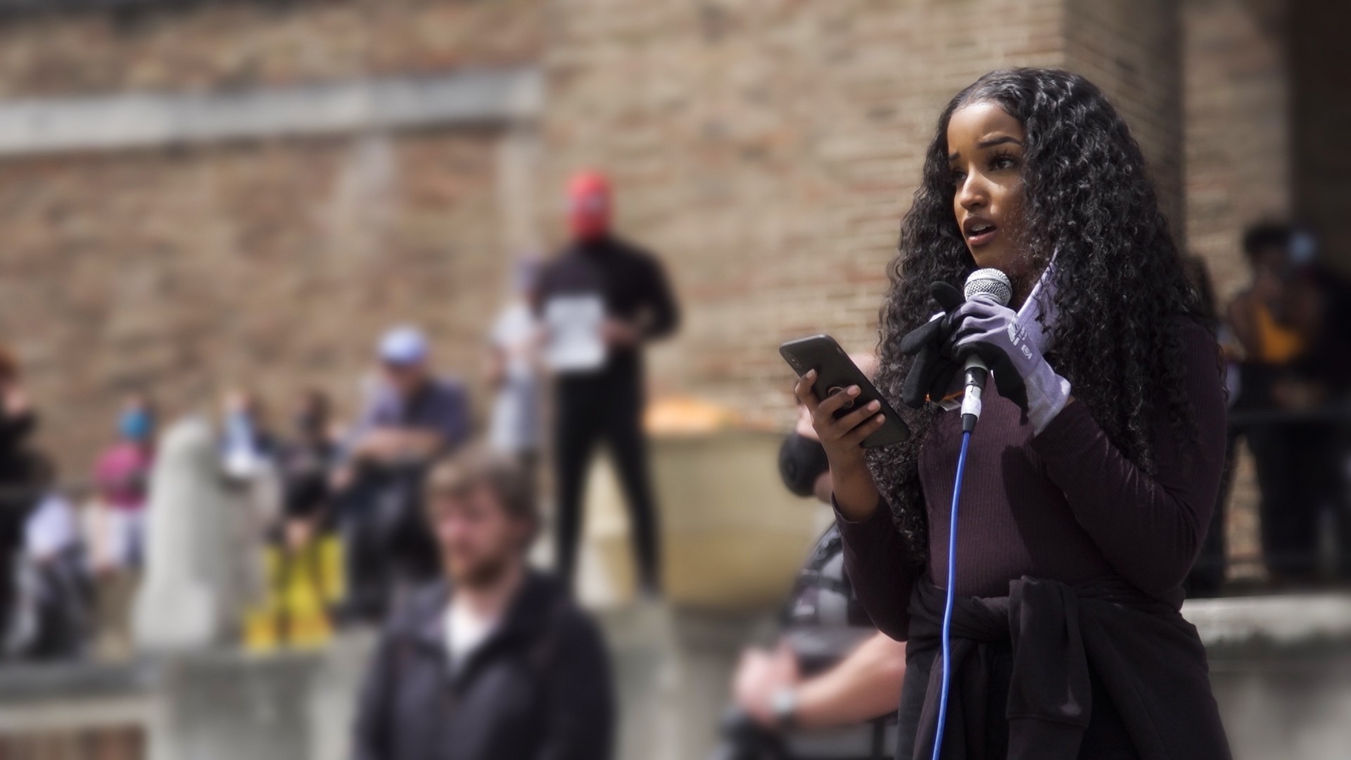 A young Black female protestor speaking into a microphone 
