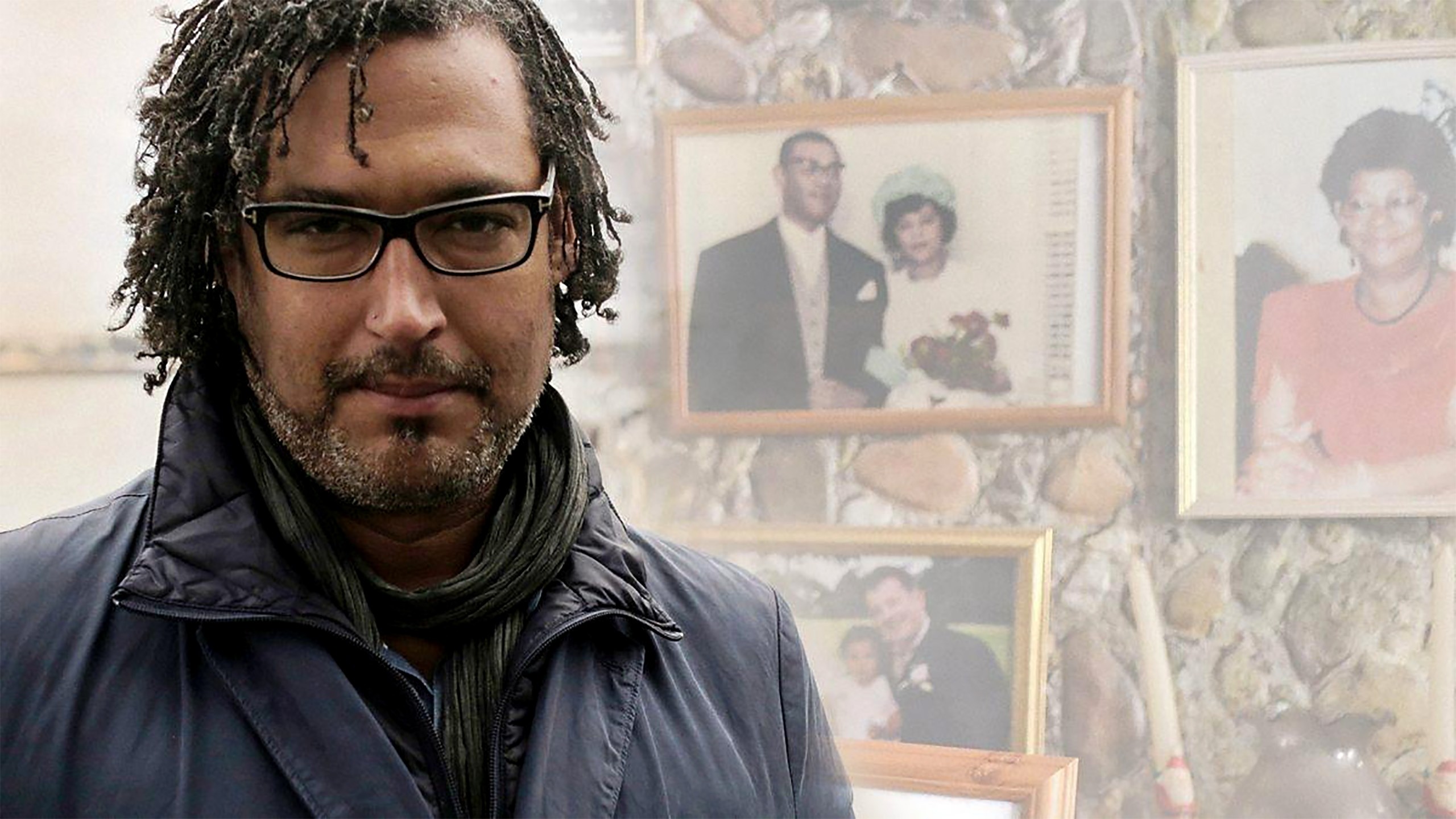 Historian David Olusoga in front of a portrait wall of Black families 