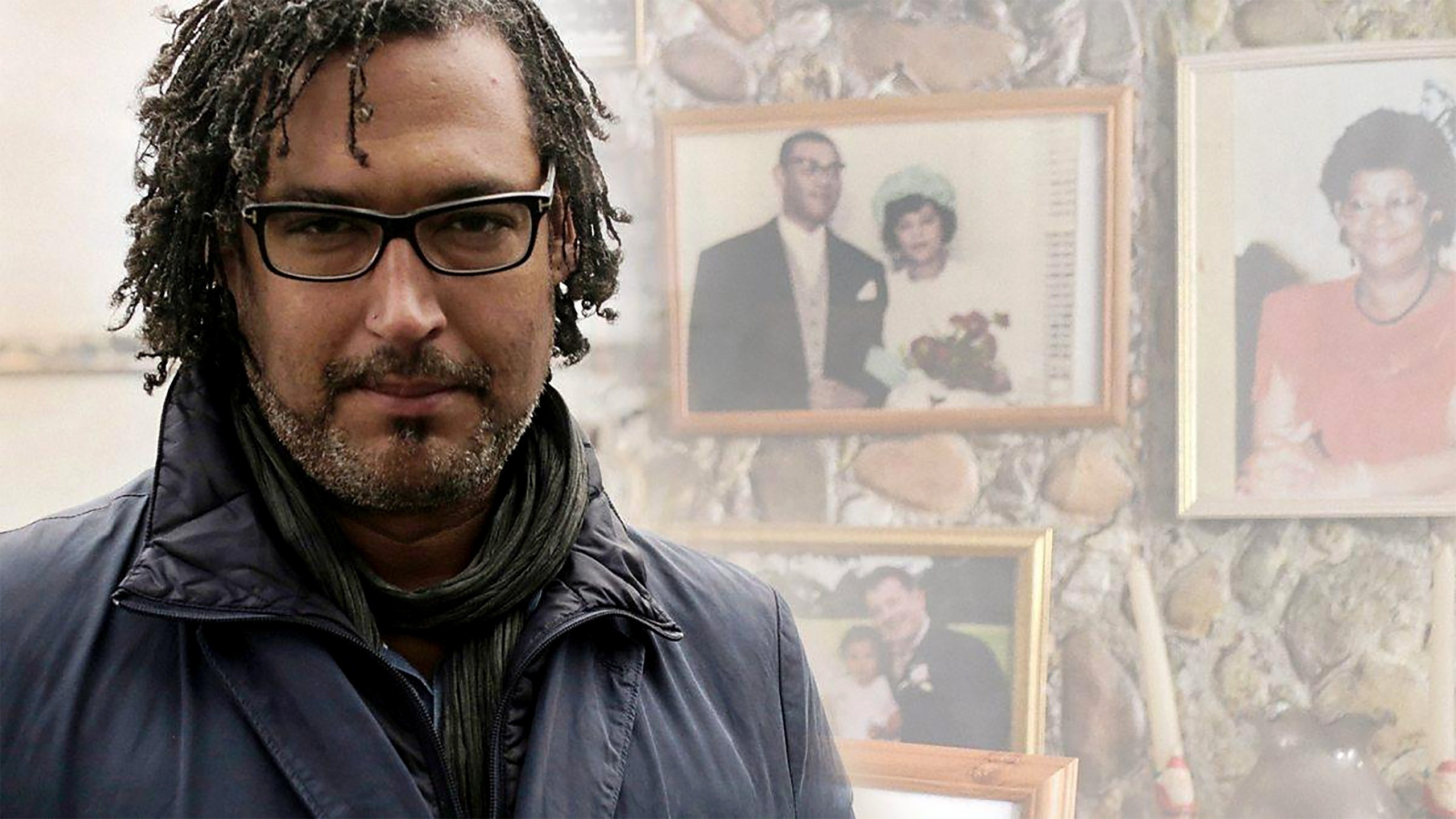 Historian David Olusoga in front of a portrait wall of Black families
