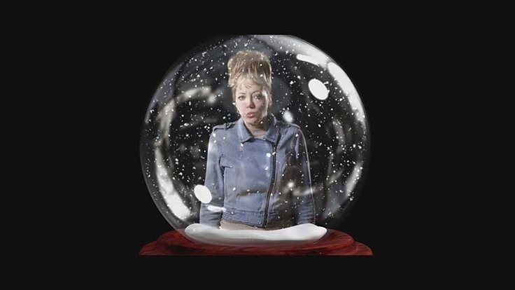 Diane Morgan as Mandy seen through a snow globe on a blackbackground