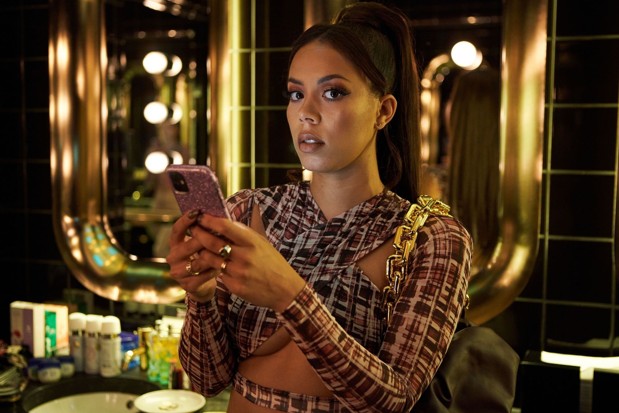 Young Black woman in a bathroom texting on her smartphone