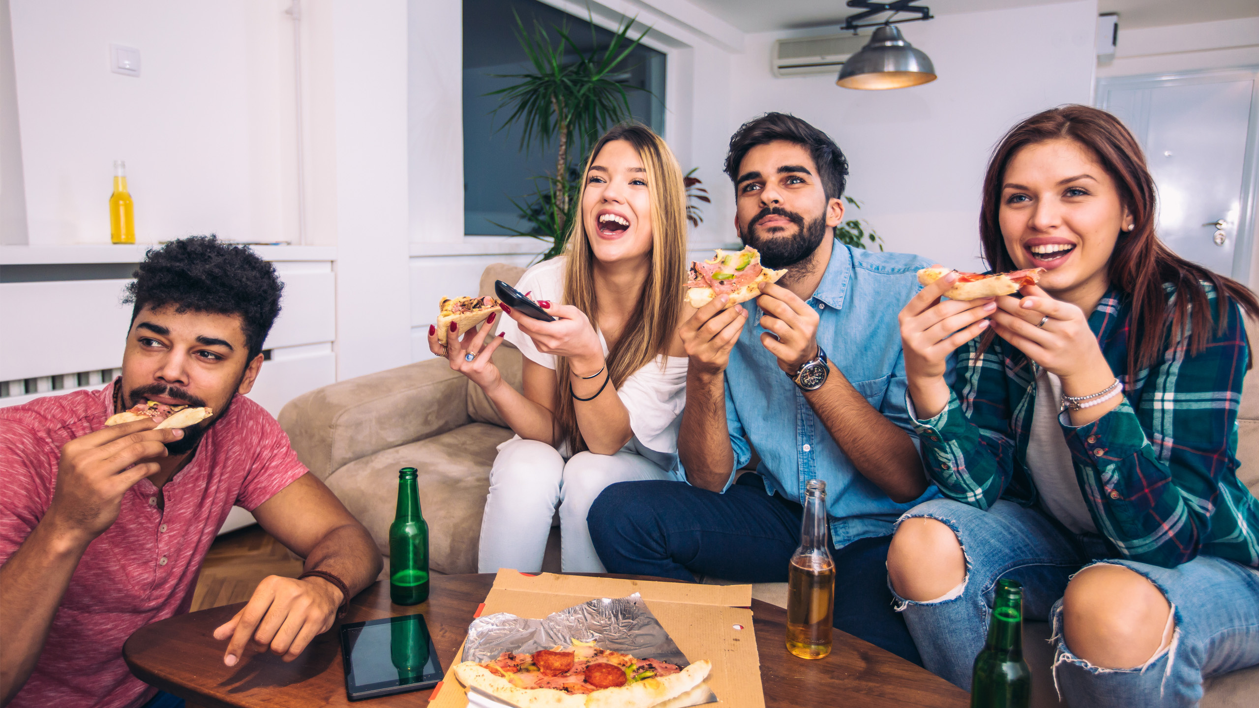 A group of friends watching TV and eating pizza