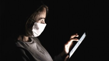 Woman wearing a face mask browsing the internet via a tablet