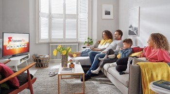 Family seated on a sofa watching Freeview Play